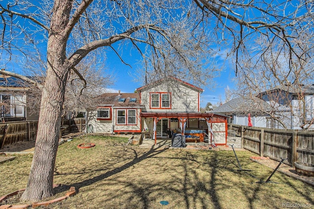 back of house featuring a patio, a fenced backyard, a lawn, and a hot tub