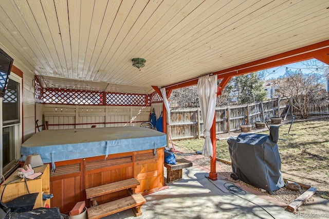 view of patio with area for grilling, a fenced backyard, and a hot tub