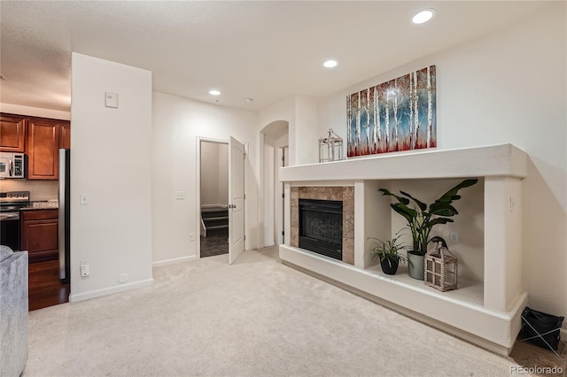 803 E 98th Ave Unit 105, Thornton, CO 80229 - unfurnished living room with arched walkways, a tiled fireplace, recessed lighting, light carpet, and baseboards