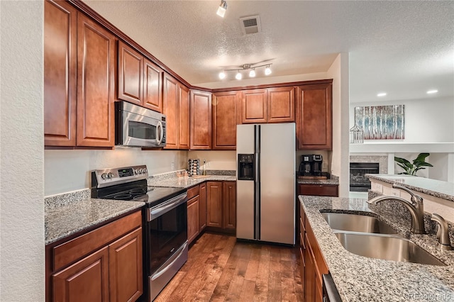 803 E 98th Ave Unit 105, Thornton, CO 80229 - kitchen with stainless steel appliances, a sink, a textured ceiling, dark wood-style flooring, and stone counters