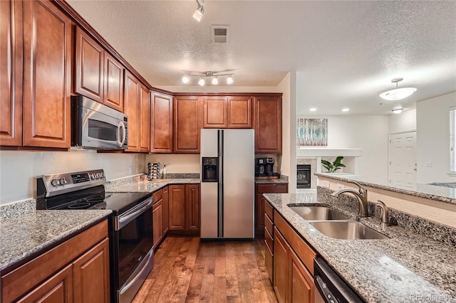 803 E 98th Ave Unit 105, Thornton, CO 80229 - kitchen featuring appliances with stainless steel finishes, a sink, a textured ceiling, wood-type flooring, and stone counters