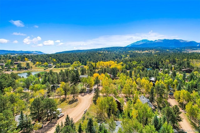 aerial view featuring a wooded view and a water and mountain view