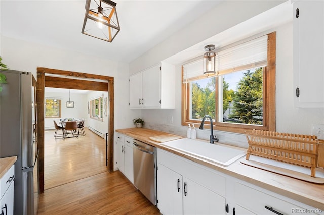 kitchen featuring a baseboard radiator, a sink, light countertops, appliances with stainless steel finishes, and plenty of natural light