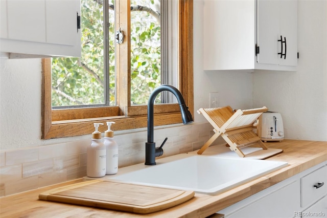 room details featuring butcher block countertops, a sink, and white cabinetry