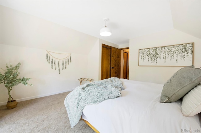 carpeted bedroom with lofted ceiling, a closet, and baseboards