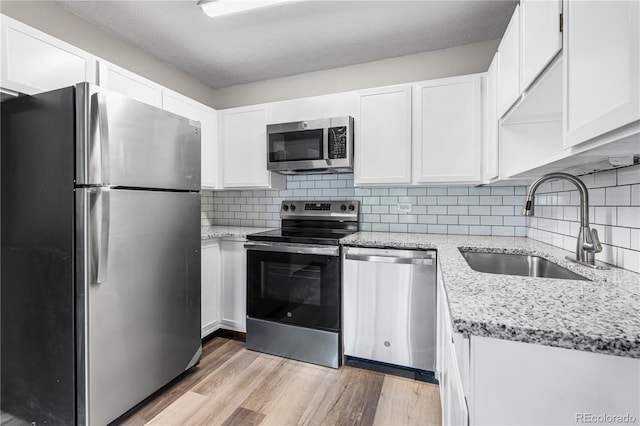 795 S Alton Way Unit 11C, Denver, CO 80247 - kitchen with stainless steel appliances, a sink, light wood-style flooring, white cabinetry, and light stone countertops