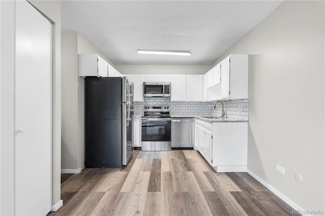 795 S Alton Way Unit 11C, Denver, CO 80247 - kitchen with stainless steel appliances, a sink, tasteful backsplash, white cabinets, and light wood-style flooring