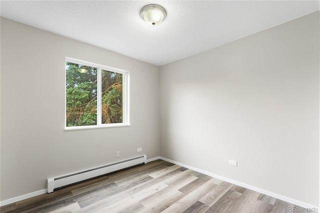 795 S Alton Way Unit 11C, Denver, CO 80247 - spare room featuring a baseboard radiator, wood finished floors, and baseboards