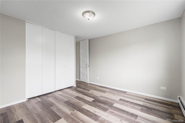 795 S Alton Way Unit 11C, Denver, CO 80247 - unfurnished bedroom with wood finished floors, a baseboard radiator, a closet, and baseboards