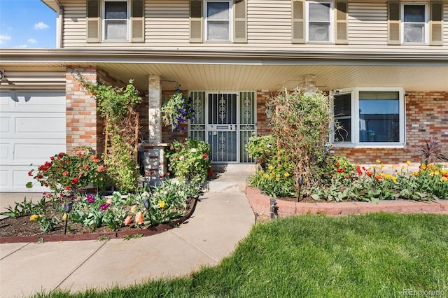 entrance to property with covered porch, brick siding, and a garage