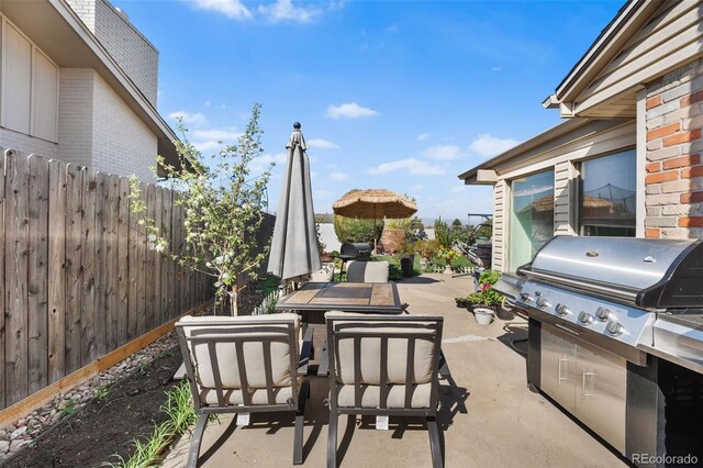 view of patio / terrace featuring outdoor dining space, fence, and a grill