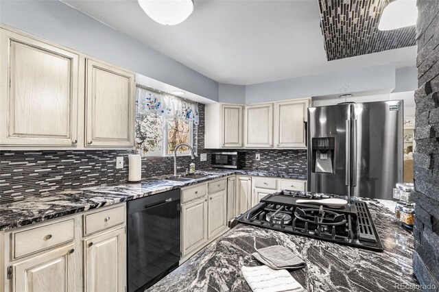kitchen featuring a sink, dark stone counters, appliances with stainless steel finishes, and backsplash