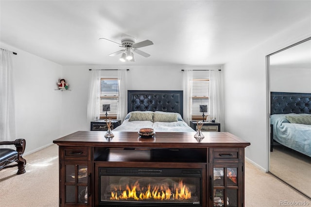 bedroom with a ceiling fan, baseboards, and light carpet