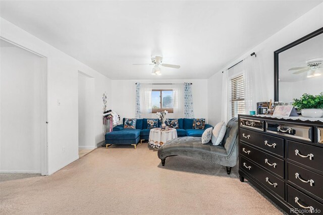 living area with baseboards, a ceiling fan, and light carpet