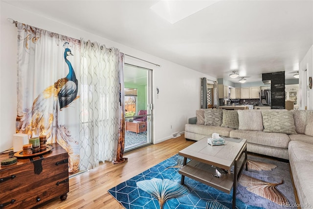 3191 S Holly Pl, Denver, CO 80222 - living room featuring light wood-type flooring, a skylight, and baseboards