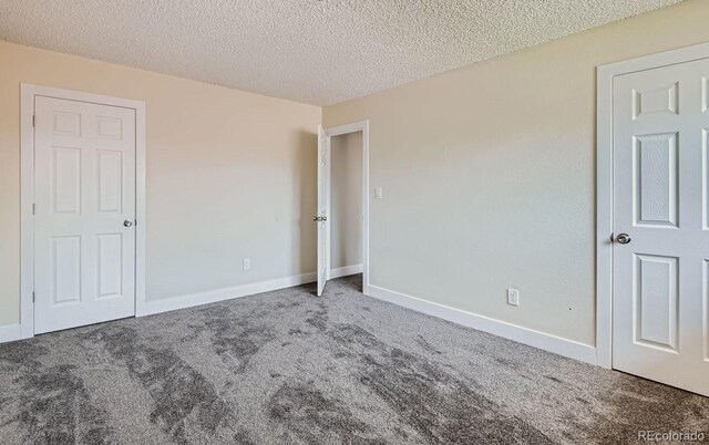 unfurnished bedroom featuring carpet floors, a textured ceiling, and baseboards