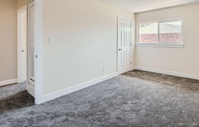 empty room featuring baseboards, a textured ceiling, and carpet