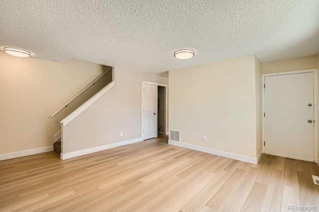 8039 Wolff St Unit E, Westminster, CO 80031 - unfurnished living room featuring light wood-style flooring, a textured ceiling, stairway, and baseboards