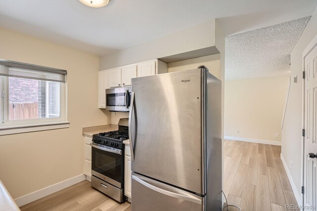 8039 Wolff St Unit E, Westminster, CO 80031 - kitchen featuring stainless steel appliances, light wood-style flooring, white cabinetry, baseboards, and light countertops