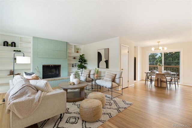 1411 Acacia Dr, Colorado Springs, CO 80907 - living area with light wood finished floors, a chandelier, a brick fireplace, a textured ceiling, and built in shelves