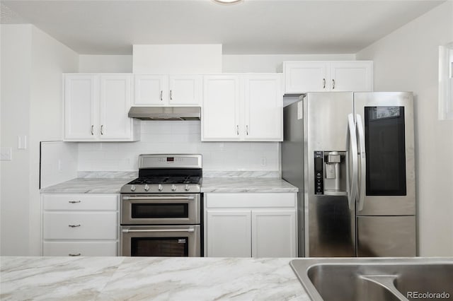 1455 W Alaska Pl, Denver, CO 80223 - kitchen with stainless steel appliances, under cabinet range hood, tasteful backsplash, and white cabinetry