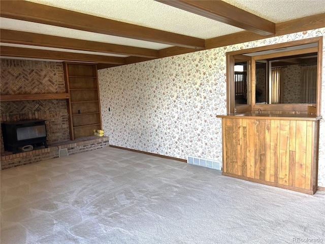 11323 E Cimmarron Dr, Englewood, CO 80111 - unfurnished living room with carpet floors, visible vents, beam ceiling, and a wood stove