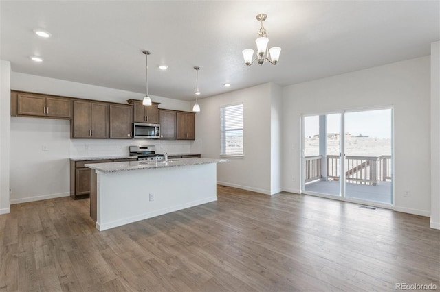 18162 Coppermallow Trl, Parker, CO 80134 - kitchen featuring appliances with stainless steel finishes, wood finished floors, an island with sink, recessed lighting, and a chandelier