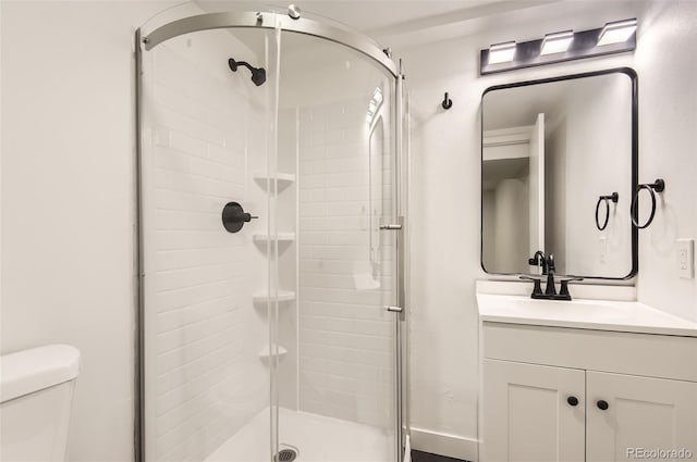 bathroom with a shower with door, vanity, and toilet