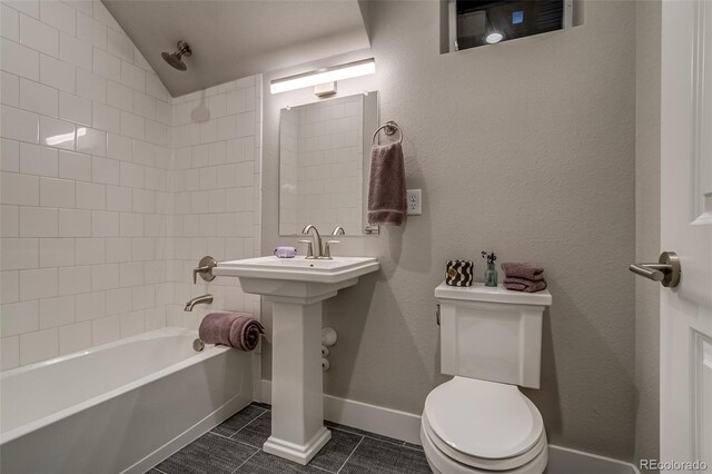 5185 Vivian St, Wheat Ridge, CO 80033 - bathroom with toilet, tile patterned floors, bathing tub / shower combination, vaulted ceiling, and baseboards