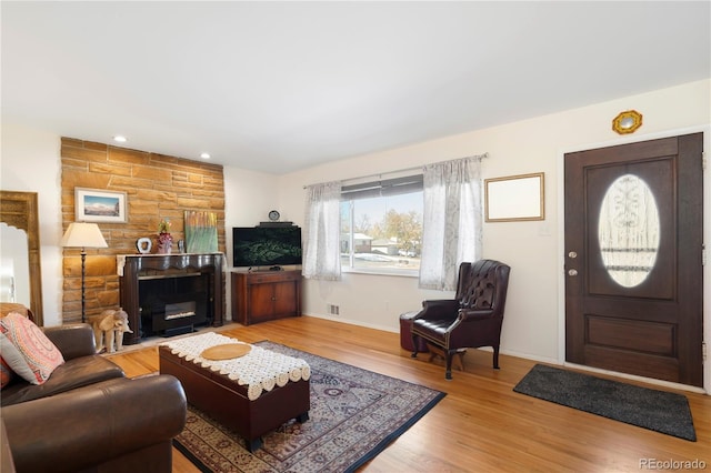 living room with light hardwood / wood-style floors and a stone fireplace