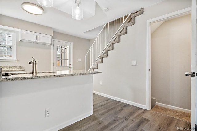 kitchen featuring white cabinetry, plenty of natural light, dark hardwood / wood-style floors, and light stone counters