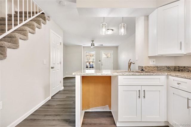 kitchen with dark wood-type flooring, sink, pendant lighting, ceiling fan, and white cabinets