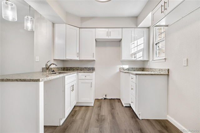 kitchen featuring white cabinetry, sink, pendant lighting, and hardwood / wood-style floors