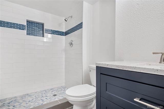 bathroom featuring vanity, toilet, and tiled shower