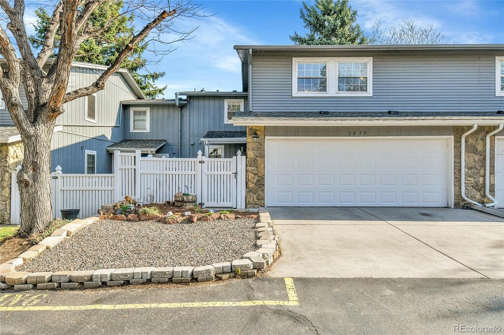 2879 S Xanadu Way, Aurora, CO 80014 - view of front of home with stone siding, an attached garage, fence, and concrete driveway