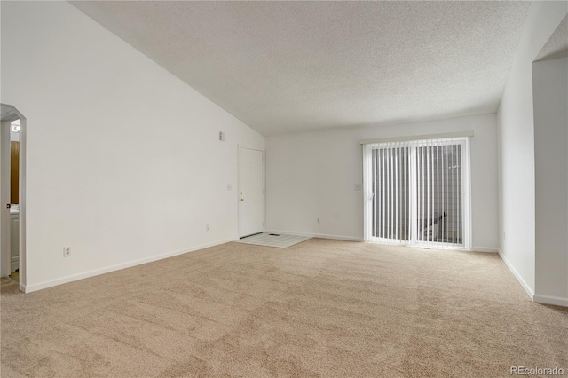 carpeted empty room with baseboards, a textured ceiling, and lofted ceiling