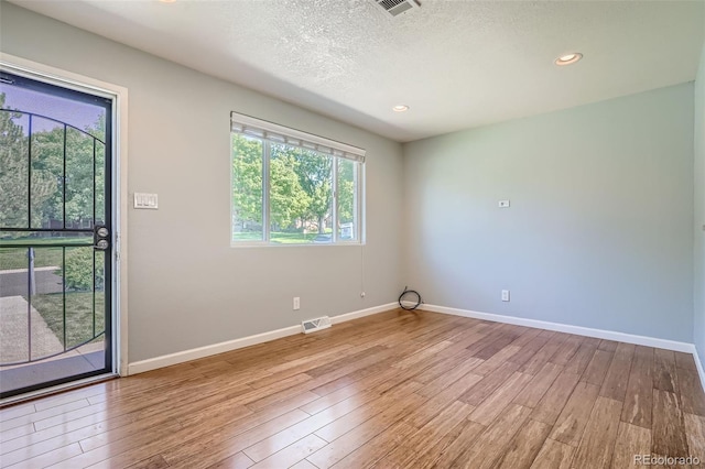 empty room featuring a textured ceiling and light hardwood / wood-style floors