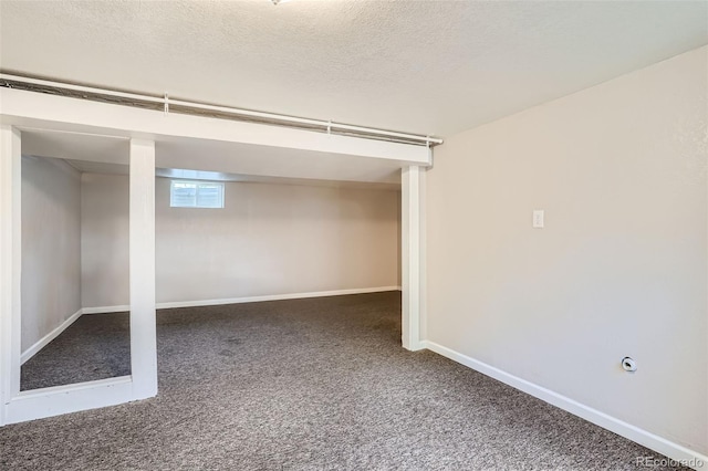 basement featuring dark colored carpet and a textured ceiling