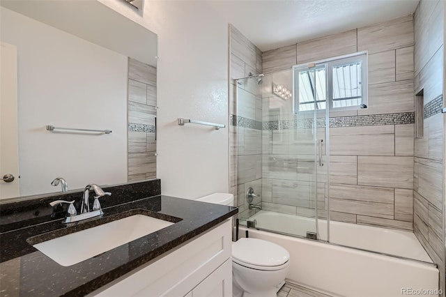 full bathroom featuring combined bath / shower with glass door, vanity, and toilet