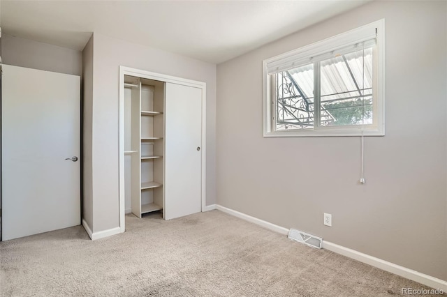 unfurnished bedroom with light colored carpet and a closet