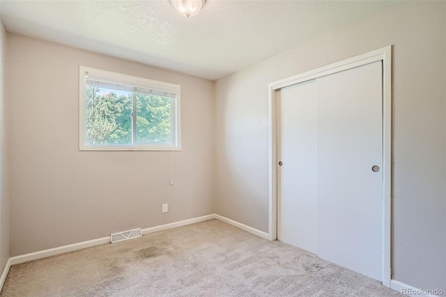 unfurnished bedroom with light carpet and a closet