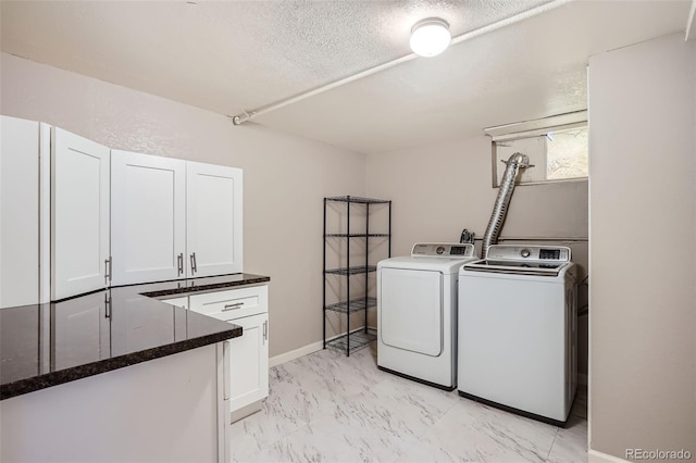 washroom with washing machine and clothes dryer, cabinets, and a textured ceiling