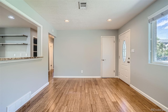 entrance foyer with a textured ceiling, light hardwood / wood-style floors, and a wealth of natural light