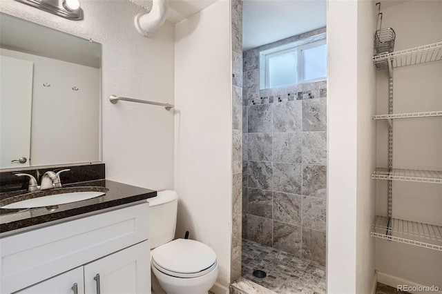 bathroom with tiled shower, vanity, and toilet