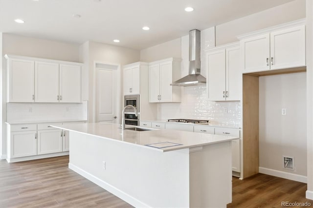 4978 Hickory Oaks St, Castle Rock, CO 80104 - kitchen featuring wall chimney range hood, a sink, white cabinets, a kitchen island with sink, and recessed lighting