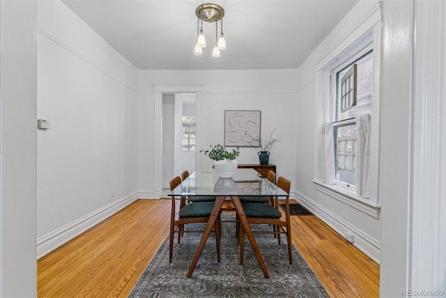 dining space featuring baseboards, a chandelier, and wood finished floors