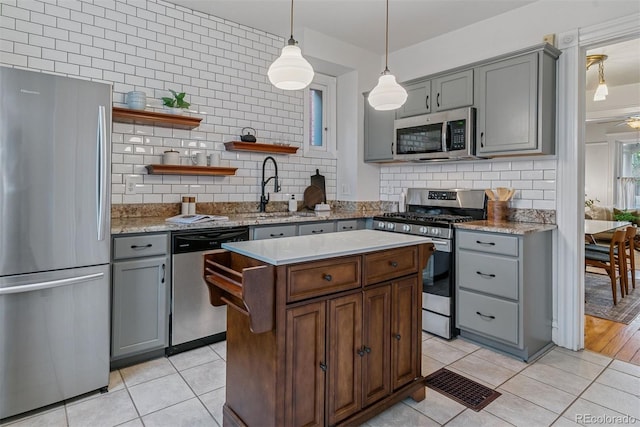kitchen with decorative backsplash, appliances with stainless steel finishes, gray cabinetry, a sink, and light tile patterned flooring