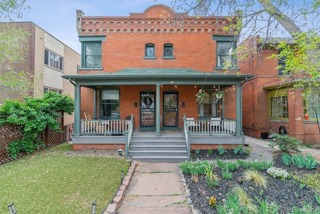 view of front of property featuring brick siding, a front lawn, and covered porch