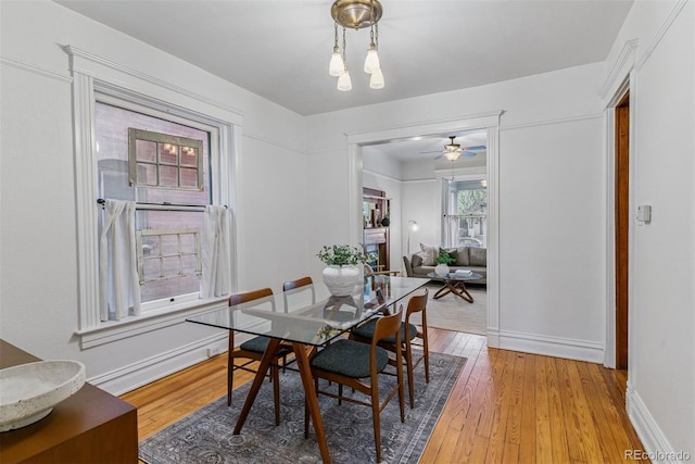 dining area with wood-type flooring, a ceiling fan, and baseboards