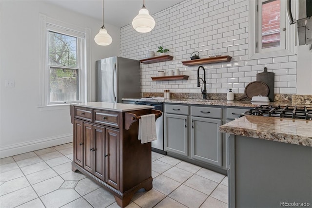 kitchen with open shelves, decorative backsplash, a sink, light tile patterned floors, and stainless steel appliances
